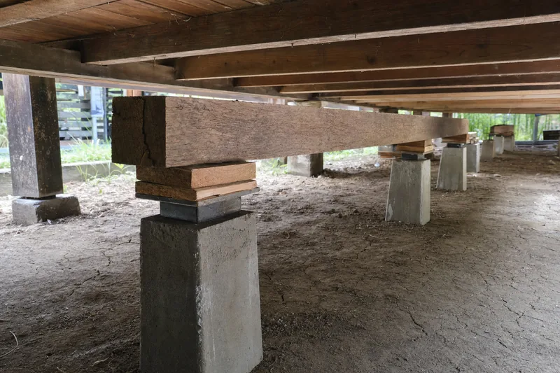 Timber packers and a steel levelling plate on a bearer under a raised house, illustrative example