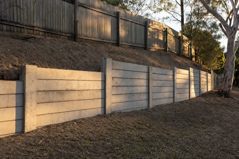 Concrete sleeper retaining wall on a sloping block with a timber fence above, illustrative example