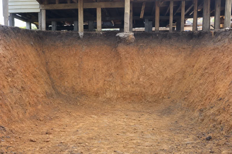 Excavated clay cut face under a raised house showing the soil profile, illustrative example