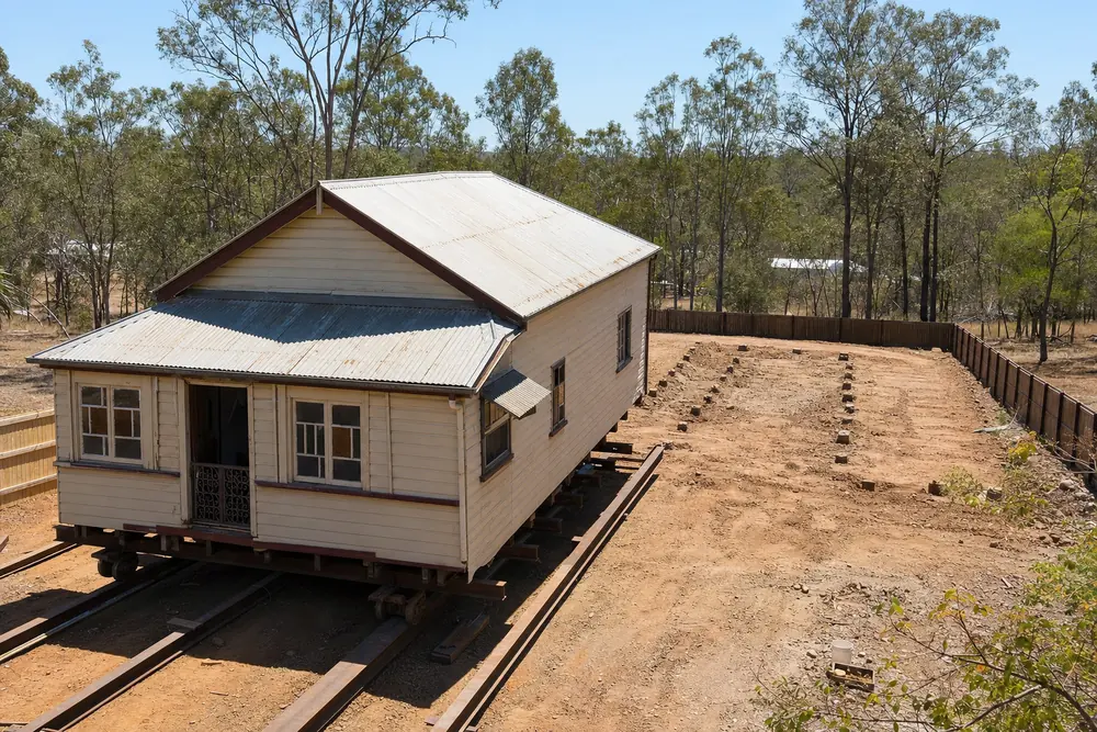 Queenslander cottage on steel rails being relocated across its block, illustrative example